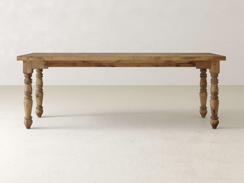 The Turned Leg Desk - Harvest Wheat by James+James features a wooden top with a rectangular shape and four intricately carved legs, set against a plain, light-colored background.