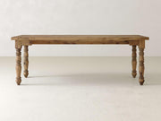 The Turned Leg Desk - Harvest Wheat by James+James features a wooden top with a rectangular shape and four intricately carved legs, set against a plain, light-colored background.