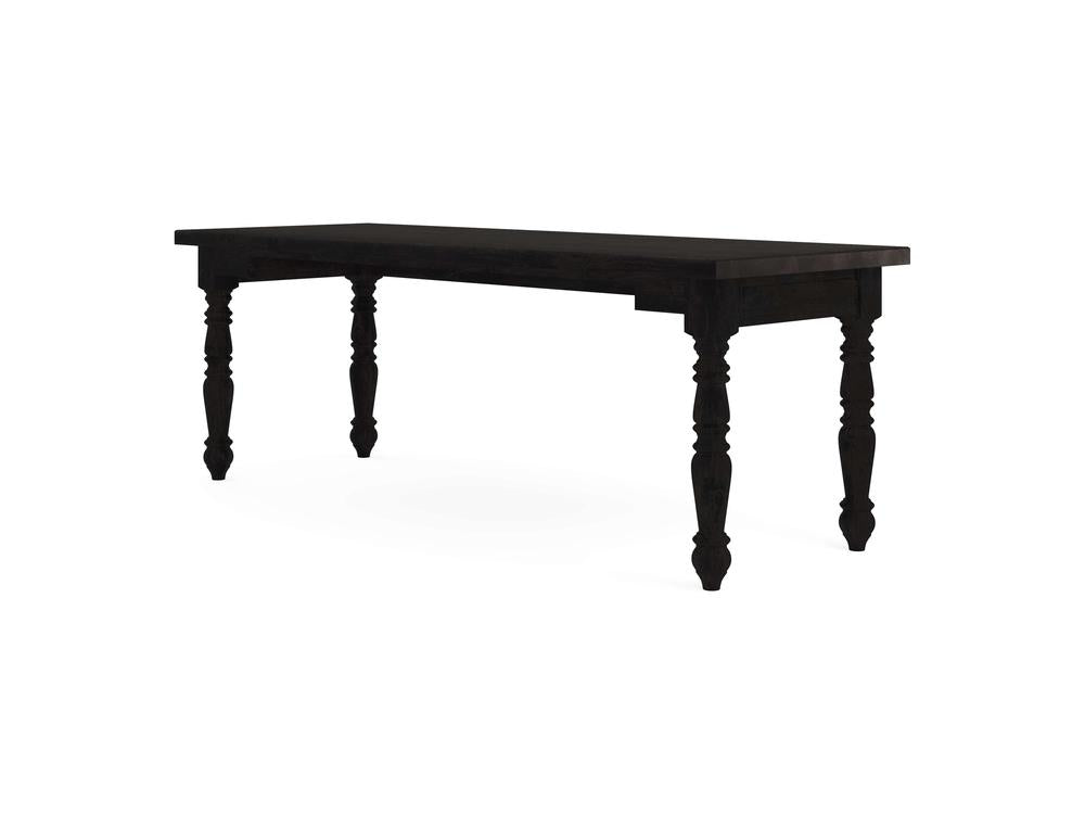 A Turned Leg Desk in Charred Ember by James+James, featuring four intricately carved legs and a smooth rectangular top, set against a plain white background.