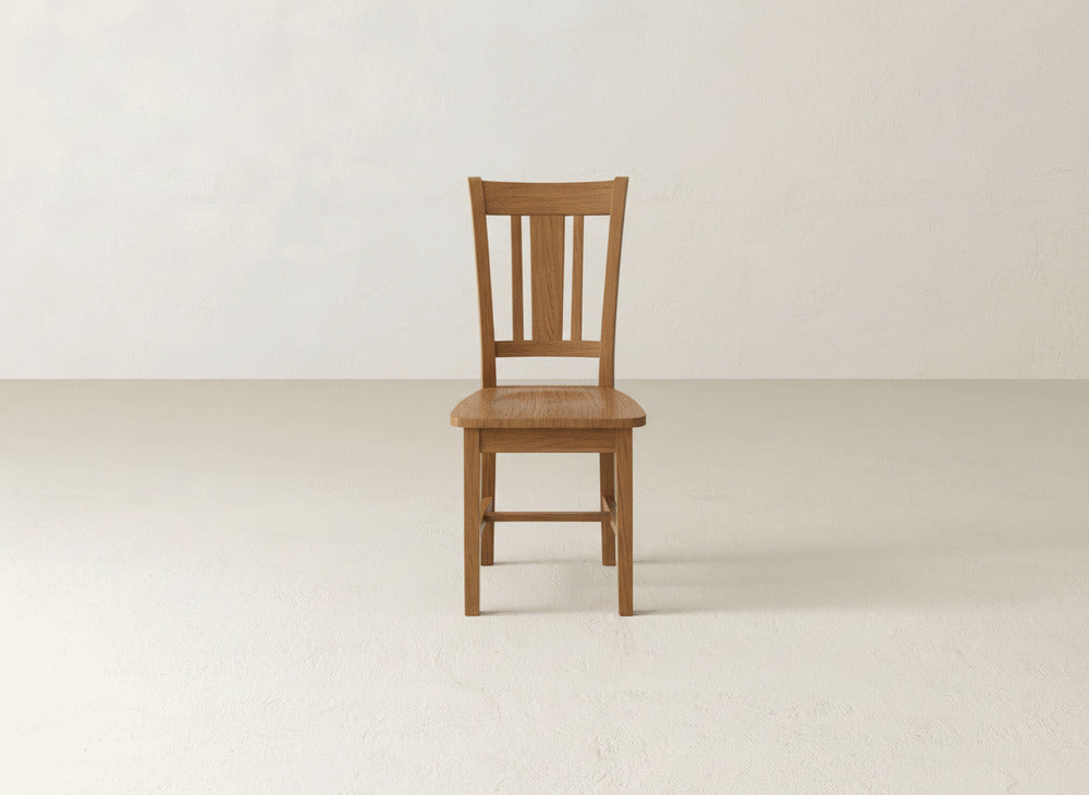 The William Dining Chair by James+James features a slatted backrest and flat seat, adding timeless elegance to any space and enhancing your decor against an off-white wall.