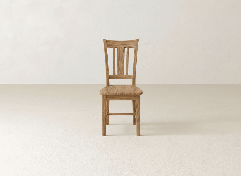 The William Dining Chair by James+James, featuring a slatted wooden backrest, is showcased in a bright, minimal room—an elegant addition for refined home decor.