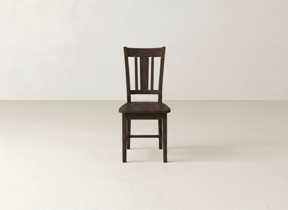 The James+James William Dining Chair, featuring a dark wood finish and slatted backrest, stands out in a light room, bringing timeless elegance to any dining area.