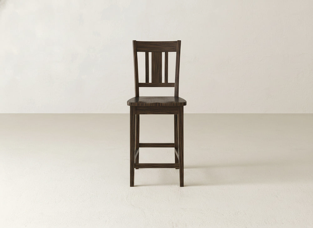 The William Stool by James & James, featuring a handcrafted dark wood design with a slatted backrest and flat seat, is centered on a light floor against an off-white wall—ideal for bringing timeless elegance to your home decor.