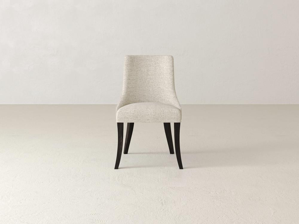 A single, modern dining chair with a light beige upholstered seat and backrest and dark wooden legs, set against a plain off-white background.