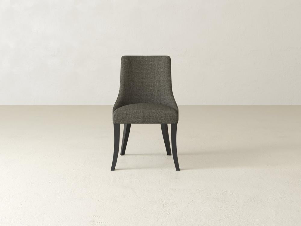 A single, upholstered chair with dark legs sits centrally in a minimalist room with beige walls and flooring. The chair has a curved back and a simple, modern design.