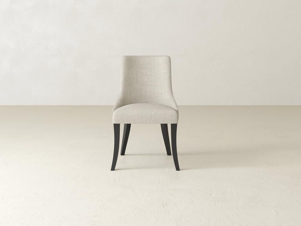 A single, modern upholstered chair with a beige fabric and dark wooden legs, placed in a minimalist setting with a light, neutral-colored background.