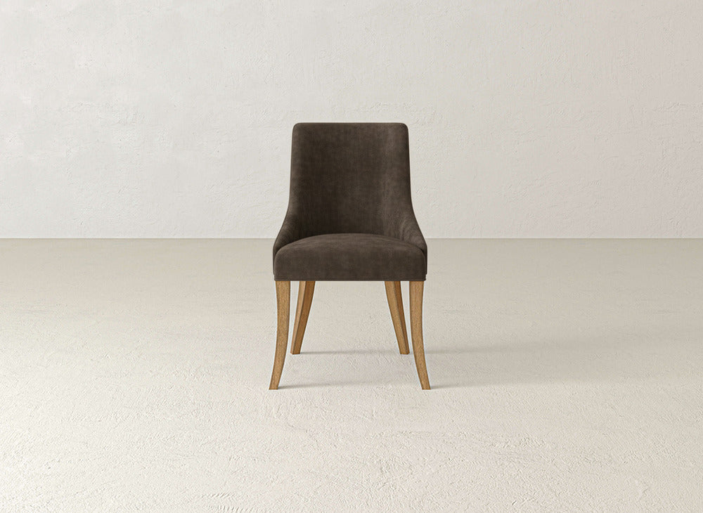 The James+James Willow Dining Chair features a dark brown upholstered seat and backrest with light wooden legs, set on a light floor against an off-white wall.