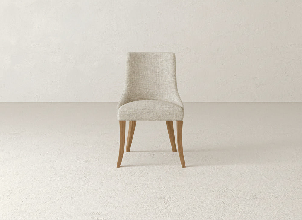 The Willow Dining Chair by James+James features light beige upholstery and wooden legs, shown on a neutral floor with an off-white backdrop.