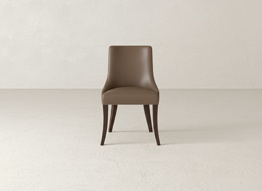 A James+James Willow Dining Chair with brown upholstery and dark wooden legs is centered in an empty, light-colored room with textured walls and floor.