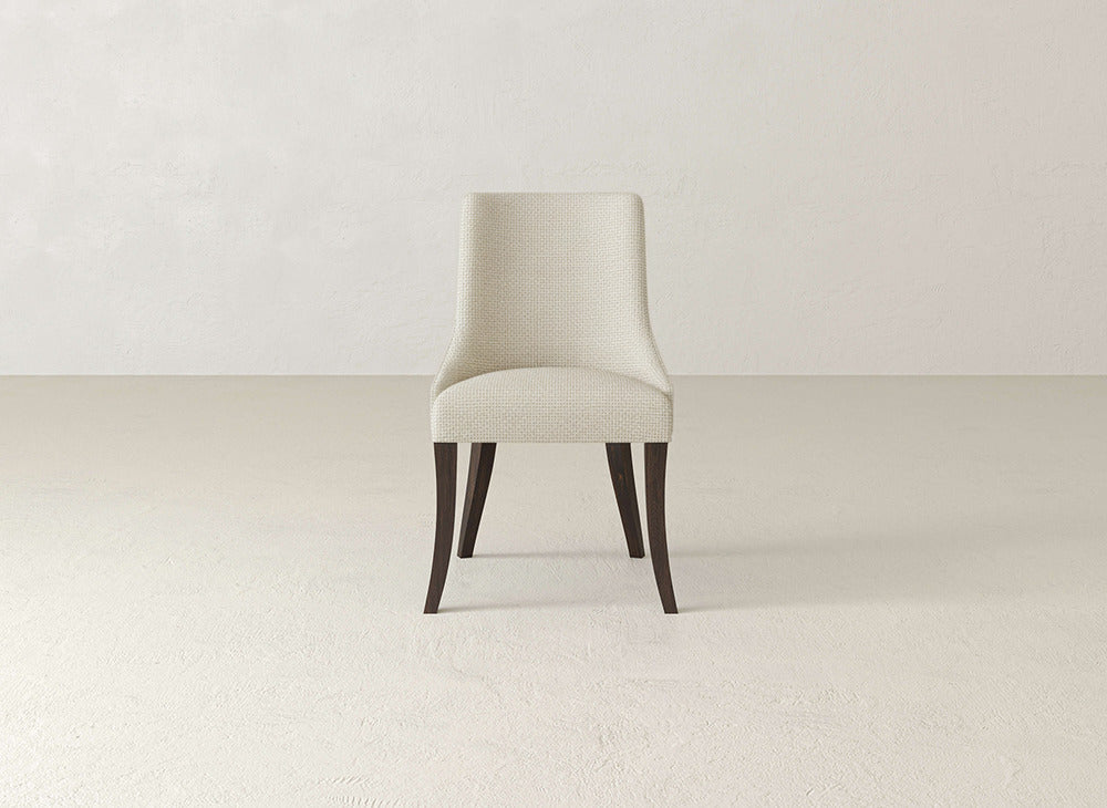 The James+James Willow Dining Chair, with light beige upholstery and dark wooden legs, is featured at the center of a minimal, neutral-toned room.
