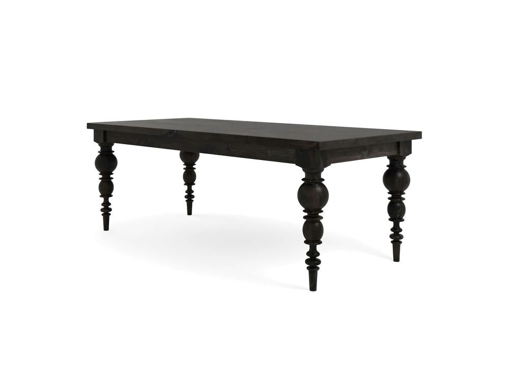 The Bailey Dining Table - Charred Ember by James+James is an elegant piece, featuring a rectangular top and four intricately carved legs with a spindle design. With its dark wood finish and classic, antique appearance, it's perfect for dining or as a statement piece in any living area.