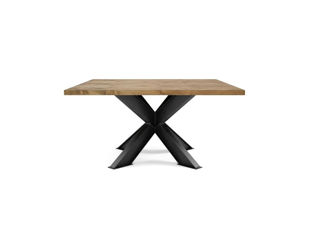 The Shiloh Square Dining Table - Harvest Wheat by James+James features a thick, natural-colored wooden top and a black, modern metal base with an intersecting X-shaped design, creating both sturdy and stylish support.