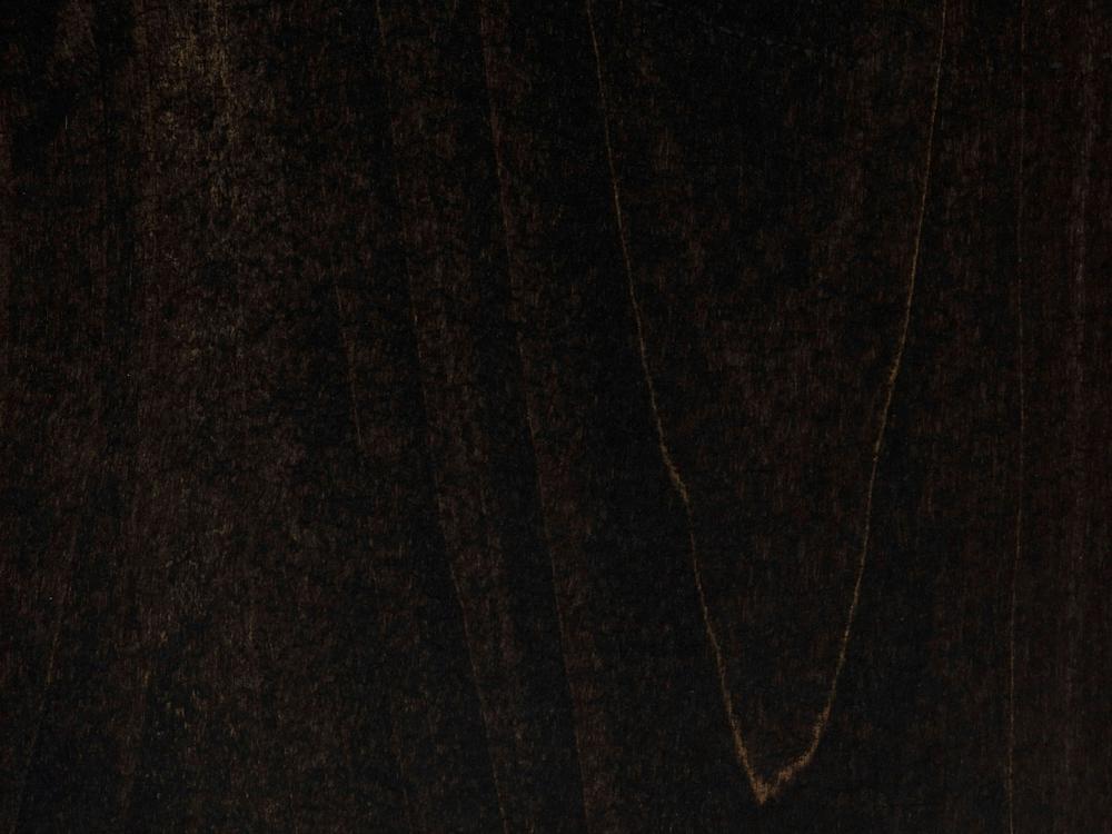 A close-up of the Audrey Desk - Charred Ember by James+James reveals a dark, textured surface that resembles wood. The image showcases a rich, deep brown color with subtle grain patterns and variations in shading. A slightly lighter, curved line runs down the middle, adding contrast to the overall dark appearance.