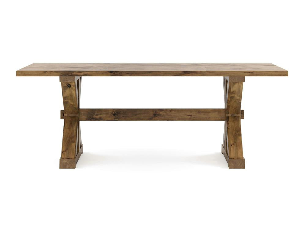The Trestle Dining Table - Harvest Wheat by James+James features a rectangular wooden design with a rustic finish. It boasts a solid top and a sturdy trestle base with cross-bracing for enhanced durability. The natural grain pattern of the wood gives it a classic look, while the two wide legs connected by a horizontal bar provide additional support.
