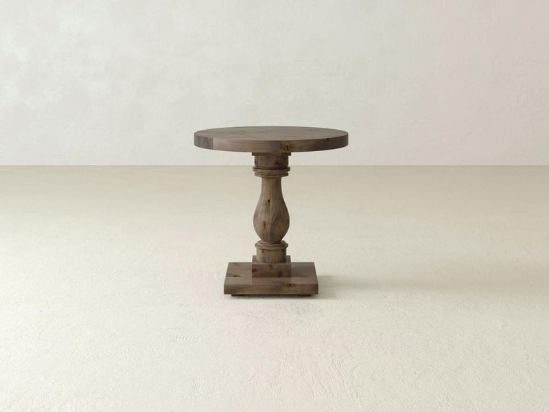 The Vivien Side Table by James+James showcases a slender, intricately carved pedestal leg and a square base, set against a plain, light-colored background.