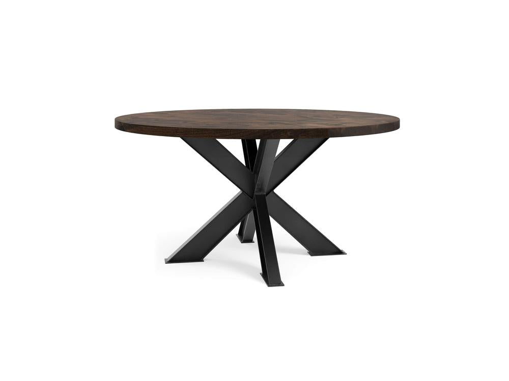 A round wooden table with a tobacco-colored top and a modern, black metal X-shaped base. The design is minimalist and contemporary, featuring clean lines and a sleek look. The legs cross at the center, providing sturdy support. The backdrop is white. This is the Shiloh Round Dining Table from James+James.