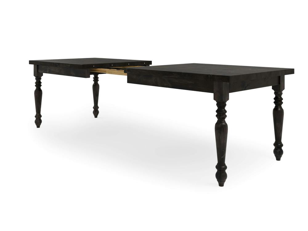 The French Country Expandable Dining Table - Charred Ember by James+James boasts an elegant and traditional design with intricate turned legs. The dark wood table is displayed in its extended position, clearly showing the gap in the center where an additional leaf can be inserted.