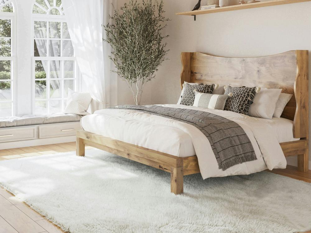 Sunlit bedroom featuring the Harlow Bed - Harvest Wheat on Alder by James+James, styled with neutral bedding, decorative pillows, a cozy throw, fluffy white rug, corner tree, and a window seat with cushions by tall arched windows.