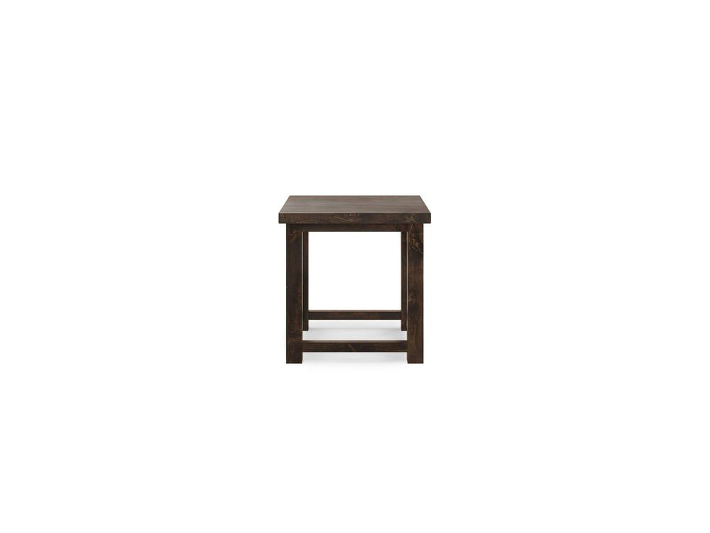 The Carter X Side Table - Tobacco by James+James is a small, dark wooden end table featuring a rectangular top and simple, sturdy legs. Its minimalist design boasts clean lines and a distinctive lower support bar connecting the legs, giving it a rustic appearance.