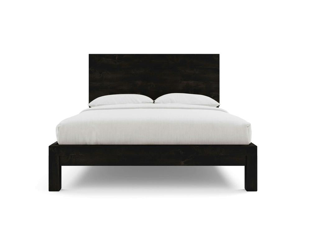 The Sawyer Bed by James+James features a dark Charred Ember alder frame and headboard, with a white mattress, bedding, and two pillows, set against a plain white background.