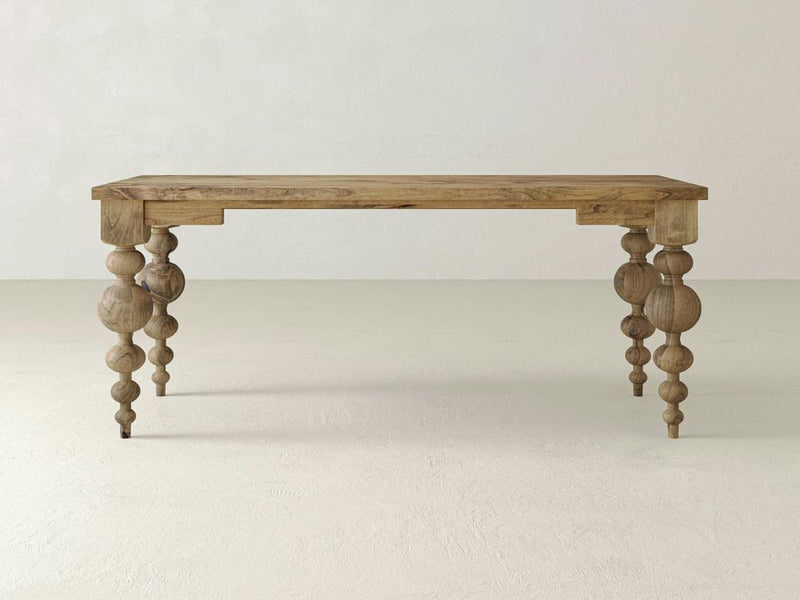 A close-up of the Olivia Desk in Harvest Wheat by James+James showcases a beautiful wooden surface with visible grain patterns and a prominent knot in the upper center. The desk features a natural light brown color with subtle variations in tone and a smooth texture.