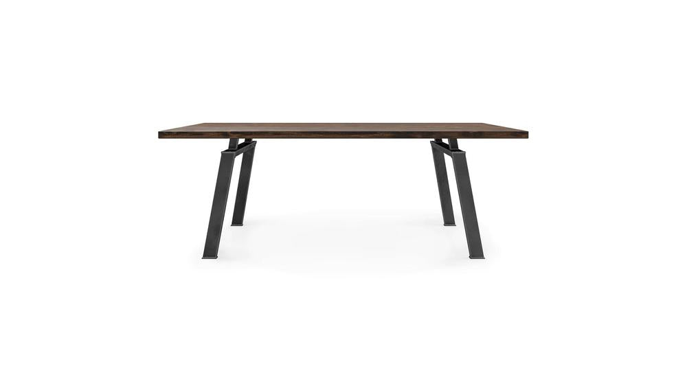 The Fulton Dining Table - Tobacco by James+James features a modern, minimalist design with a rectangular wooden top in a dark brown hue and sleek black metal legs. This table is characterized by its straight lines and robust construction. The product image showcases the table against a plain white background.
