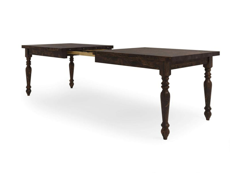 The French Country Expandable Dining Table - Tobacco by James+James is depicted with its dark wooden surface and intricately carved legs, showcasing an extendable mechanism in the middle that allows for added length. The table exudes a classic, elegant design.
