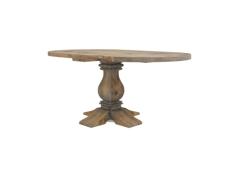 Heirloom Oval Dining Table - Harvest Wheat by James+James. This rustic wooden table boasts an oval top and a single, elegantly carved pedestal base. The wood showcases a natural, slightly worn finish, enhancing its vintage charm. The table is supported by a sturdy, cross-shaped base.