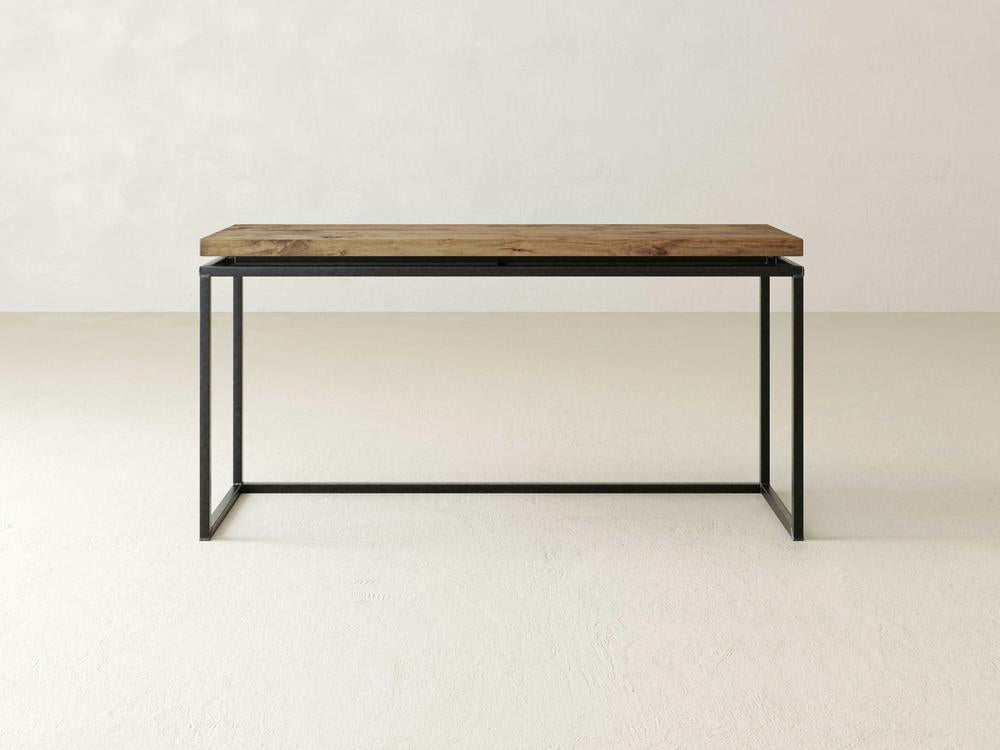 Introducing the Floating Top Sofa Table - Harvest Wheat by James+James. This modern console table features a thick wooden top with a natural wood finish and a minimalist black metal frame. The rectangular tabletop is expertly crafted, while the metal frame, composed of thin legs and supports, lends the table a sleek and contemporary design.