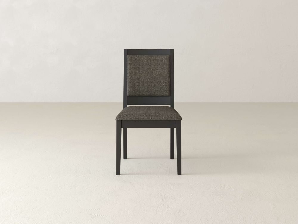 The Gina Side Dining Chair by James+James, crafted from sleek black maple wood, includes a padded seat and backrest, elegantly set against a plain, light-toned background.